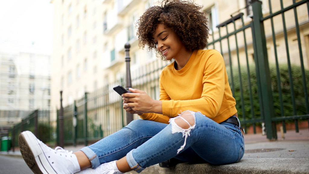 Happy young woman sitting and texting 
